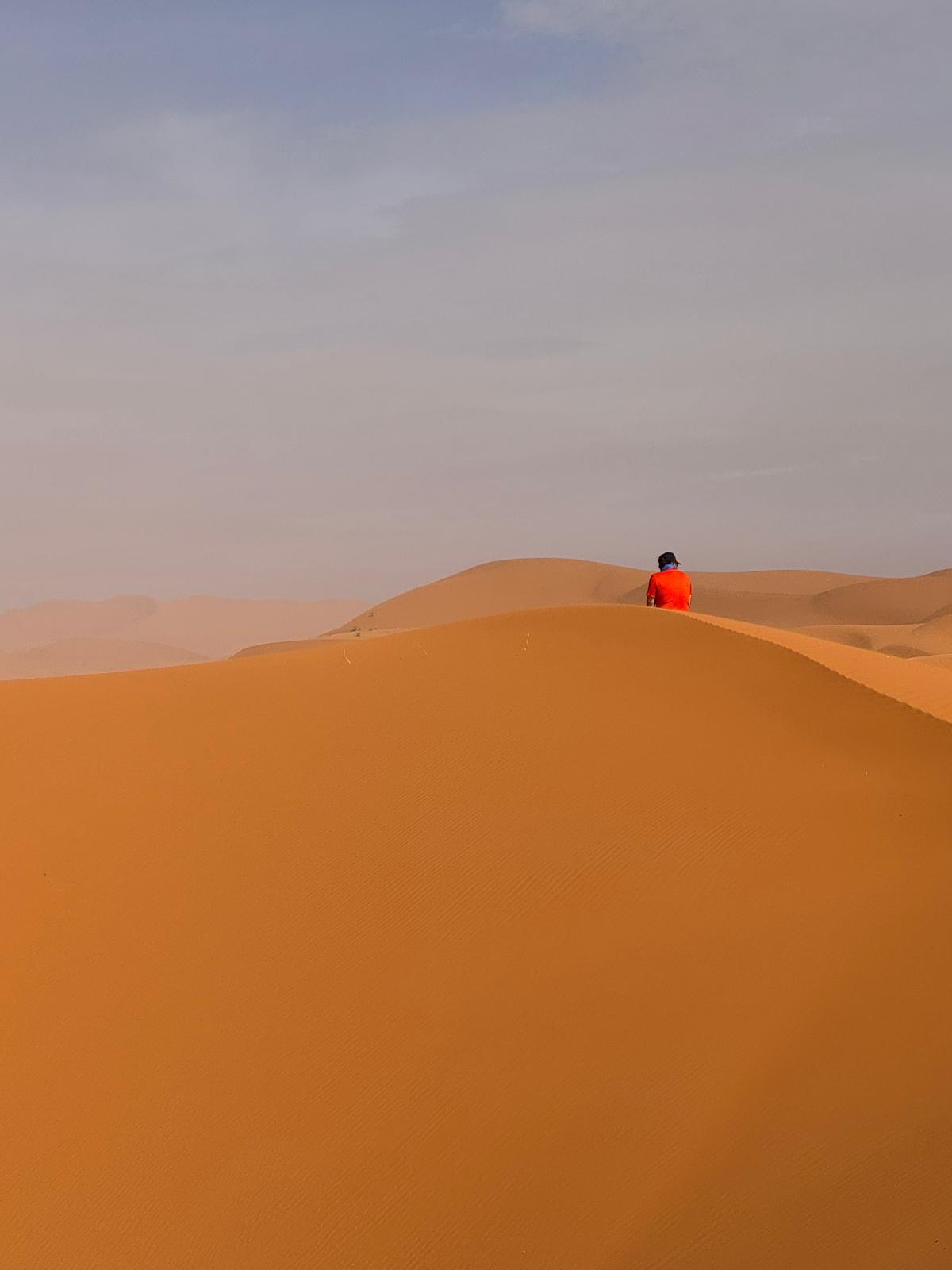 Marcheur solitaire sur la crête d'une dune au lever du jour, désert marocain