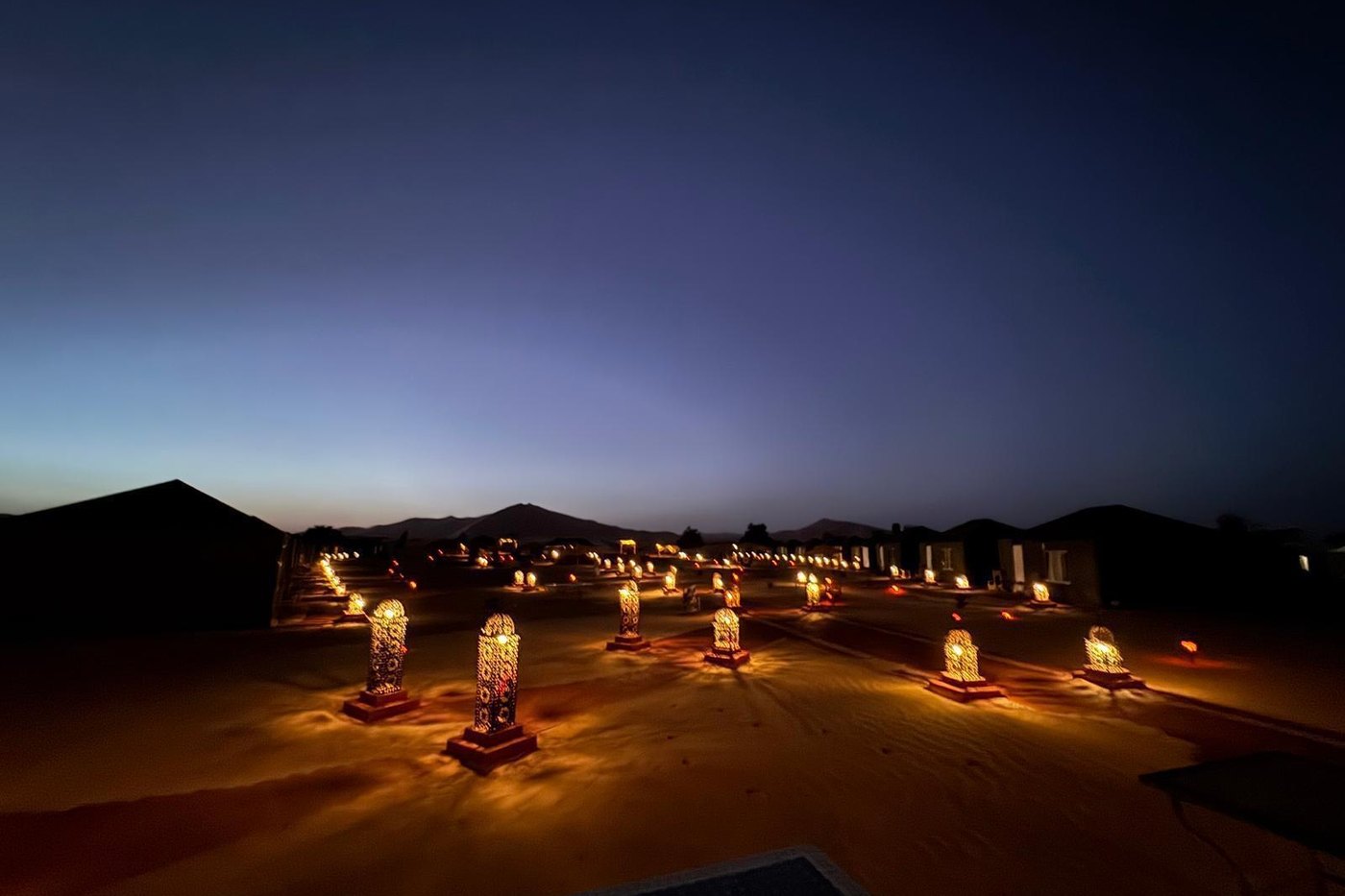 Bivouac dans le désert marocain éclairé de lanternes au crépuscule
